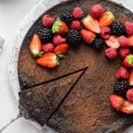 A slice being removed from a flourless dark chocolate cake