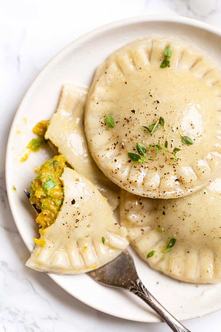 This Italian gluten free ravioli recipe with herby butternut-spinach filling is a comforting weeknight dinner that's also dairy free. Three gluten free ravioli with butternut-spinach filling on a serving plate.