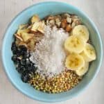 Breakfast cereal bowl with banana slices, shredded coconut, and almonds.