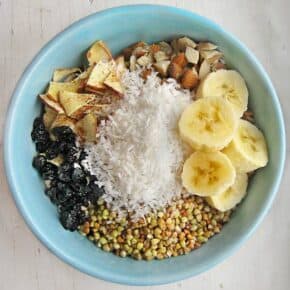 Breakfast cereal bowl with banana slices, shredded coconut, and almonds.