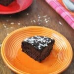 Slice of quinoa chocolate cake on an orange plate.