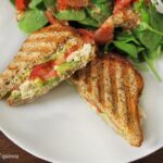 Grilled chicken and avocado panini on a plate.