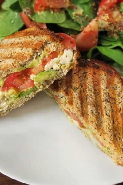 Grilled chicken and avocado panini on a plate.