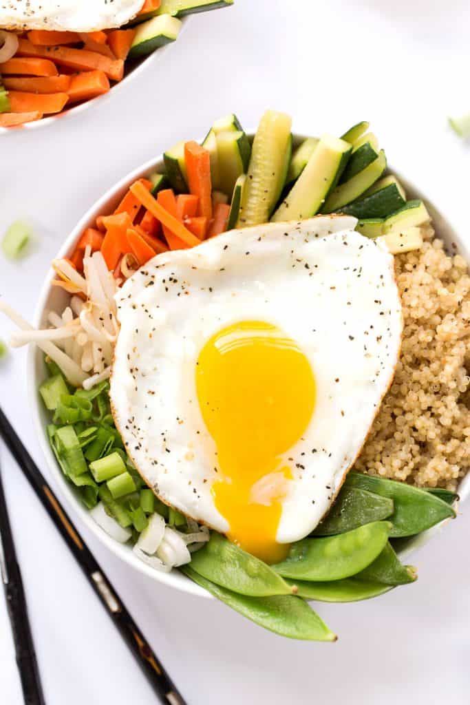 Bowl of quinoa bibimbap with steamed veggies and sunny side up egg