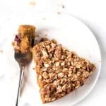 Overhead image of a slice of lemon blueberry coffee cake on a plate with a fork taking a bite from it.