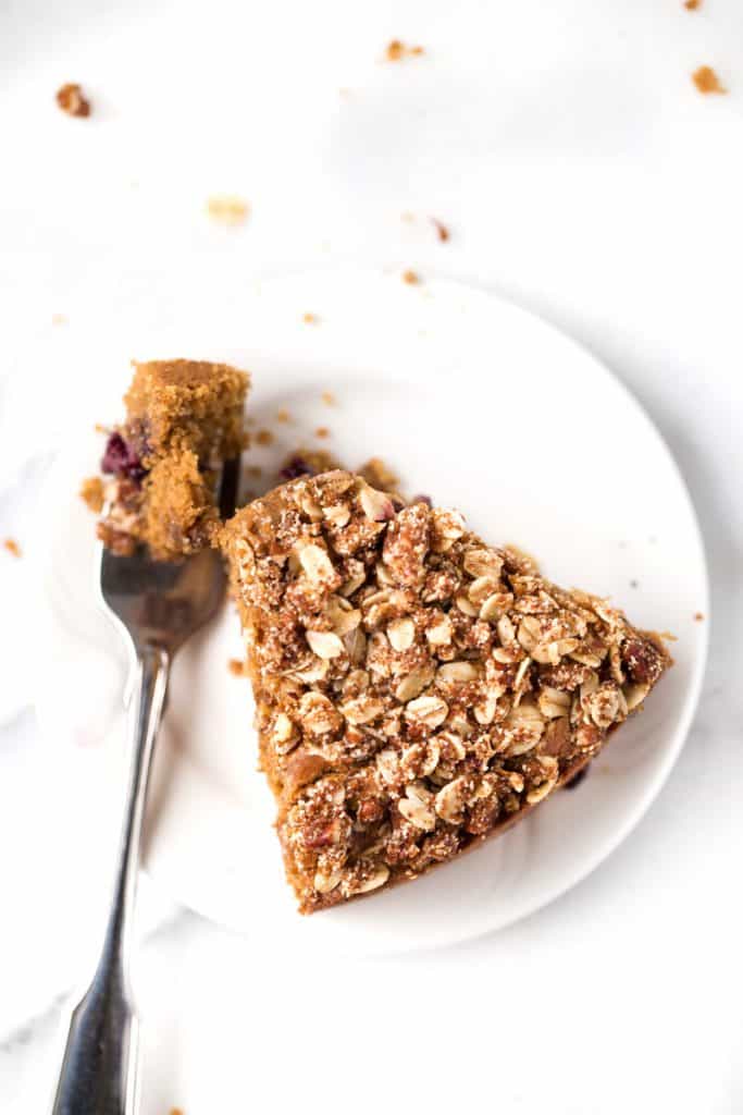 Overhead image of a slice of lemon blueberry coffee cake on a plate with a fork taking a bite from it.