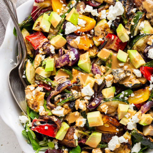 close up on a large bowl of grilled vegetable salad with tahini dressing and feta cheese