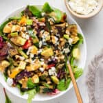 white bowl of grilled vegetables, salad dressing and feta cheese on the side