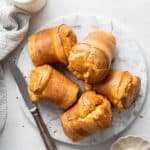 A plate with five gluten-free popovers on it, with a butter knife on the plate, next to a kitchen towel