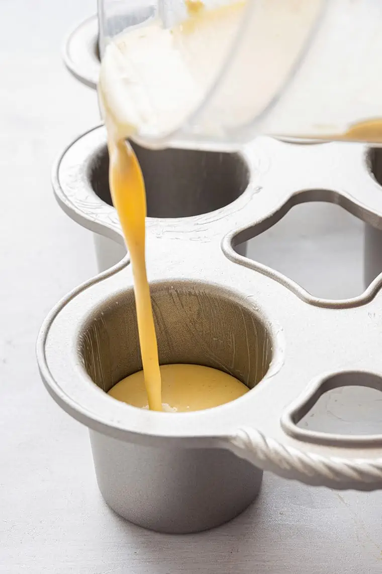 Close up of a jar pouring popover batter into a popover pan