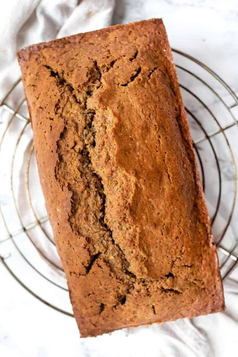 Loaf of gluten-free zucchini bread on wire rack.