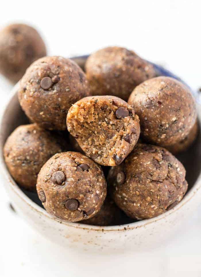 A bowl of energy ball with chocolate chips, with a bite taken out of one of them 