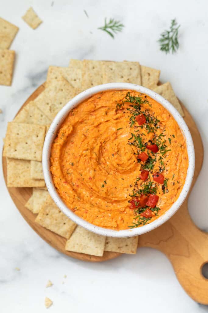 An easy smoked salmon spread flavored with roasted red peppers, fresh lemon, and dill. Serve as a dip with crackers or as a sandwich spread. Overhead view of a bowl of smoked salmon spread surrounded by crackers.