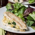 Quinoa and goat cheese stuffed chicken on a plate with salad.