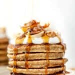 Side view of syrup being poured over stack of quinoa banana pancakes