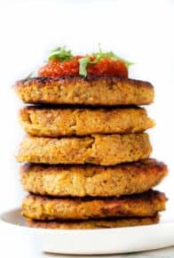 A stack of spaghetti squash fritters topped with salsa on a white plate.