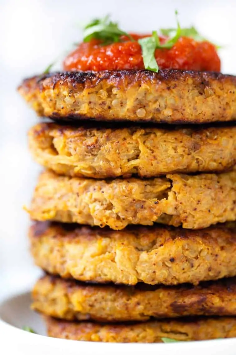 A stack of spaghetti squash fritters topped with salsa on a white plate.