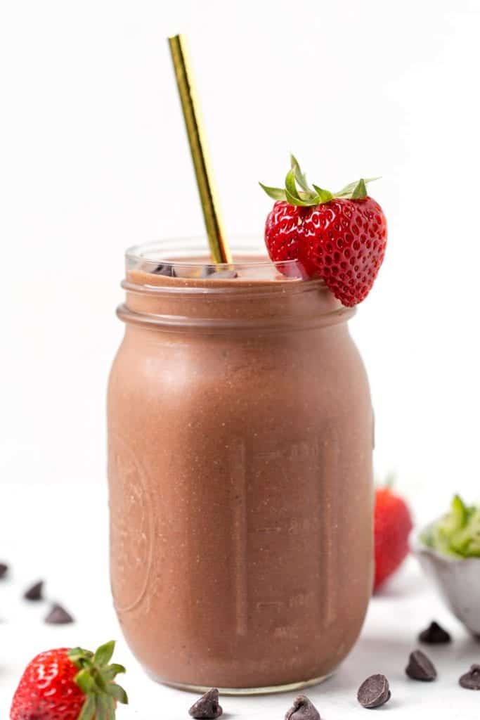 Chocolate strawberry smoothie in a glass jar with a straw.