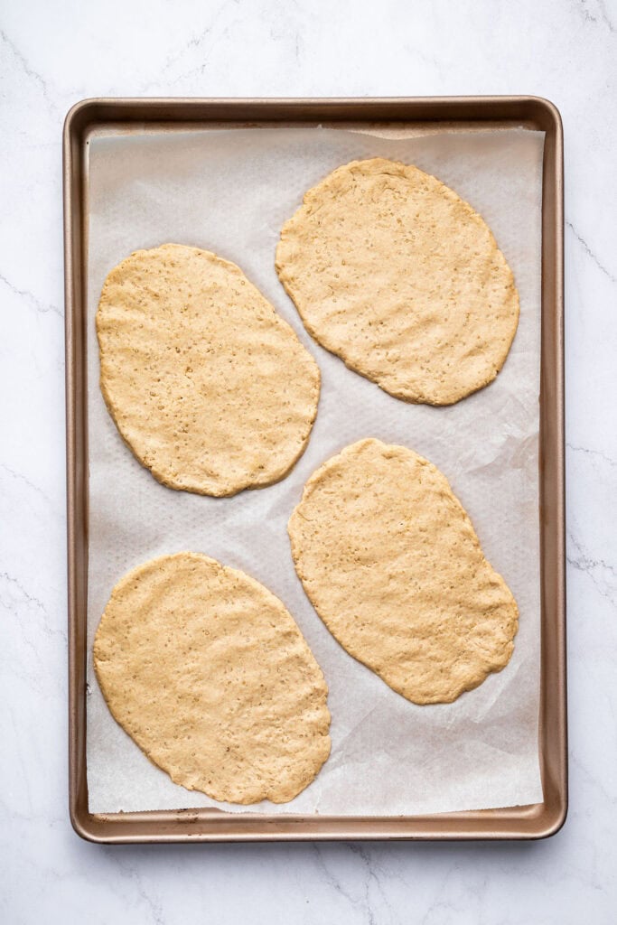Unbaked gluten-free naan on parchment-lined baking sheet