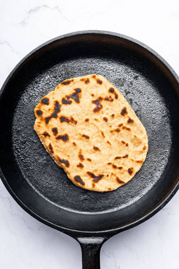 Overhead view of gluten-free naan cooking in skillet