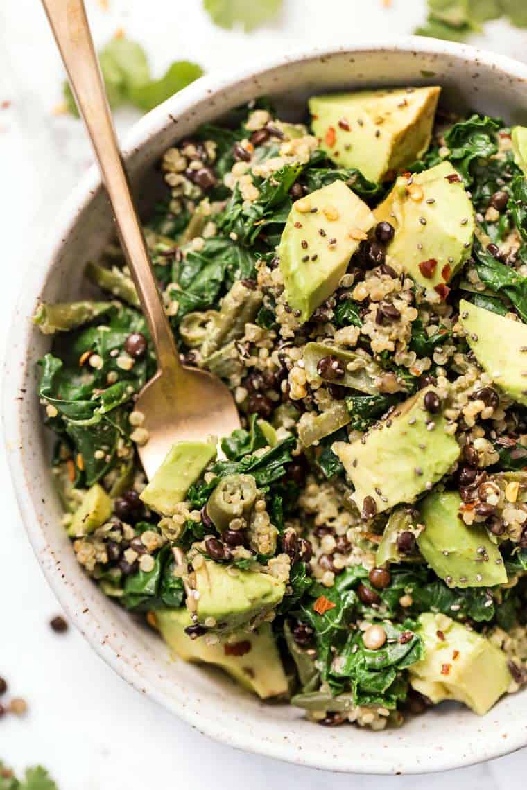 Overhead view of kale quinoa salad in a bowl with a spoon for serving.