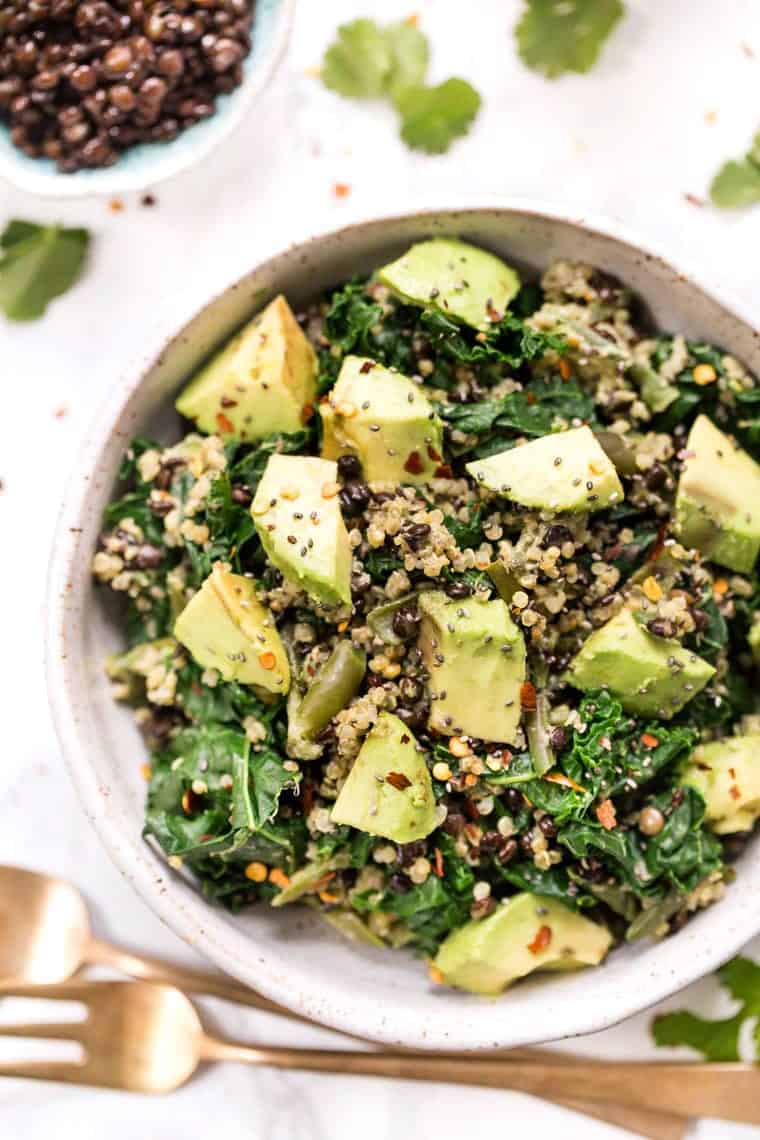 Overhead view of kale quinoa salad in a bowl next to a fork.