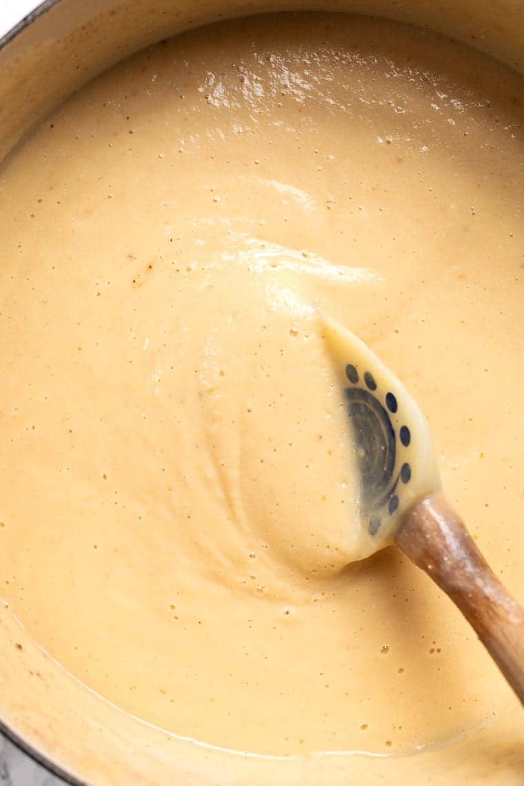 Cauliflower soup in a pot, being stirred by a rubber spatula