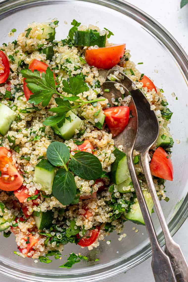 This healthy quinoa tabbouleh salad is light, refreshing, and flavorful. It's also quick and easy, requiring only a few simple ingredients! overhead of a glass bowl with quinoa, cucumbers, fresh herbs, and toamtoes