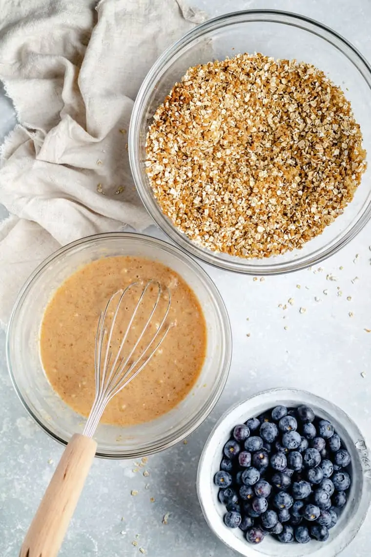 overhead of three bowls with the wet and dry ingredients and fresh blueberries