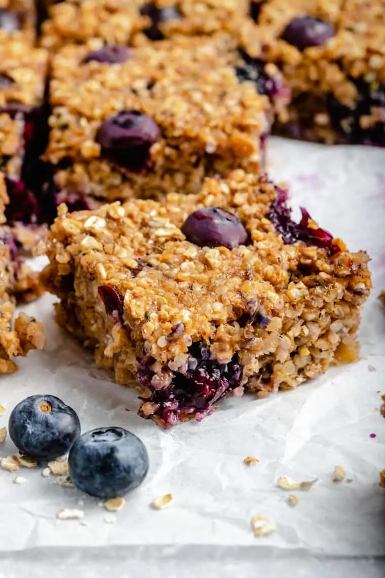 close up on a cut blueberry breakfast bar with fresh blueberries and quinoa