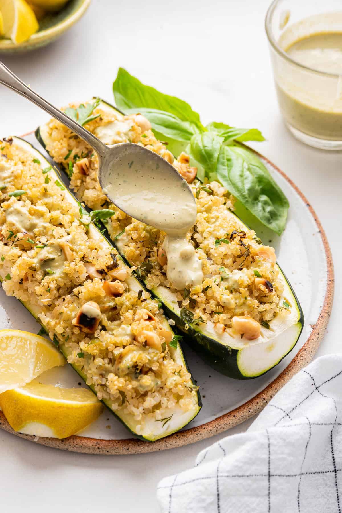 Spooning tahini onto stuffed zucchini boats