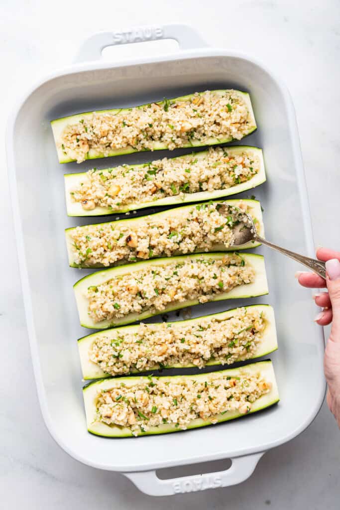 Spooning quinoa filling into zucchini boats
