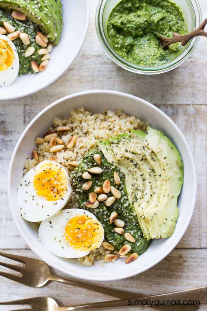 Savory Pesto Quinoa Breakfast Bowls topped with a soft boiled egg, sliced avocado and toasted pine nuts | recipe on simplyquinoa.com