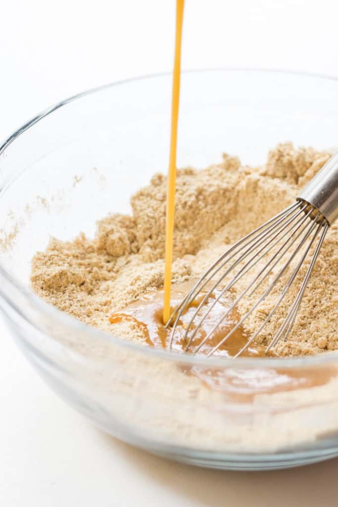Pouring liquid ingredients into bowl of dry ingredients for graham crackers