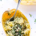 A fork stuck into spaghetti squash filled with quinoa and pesto.