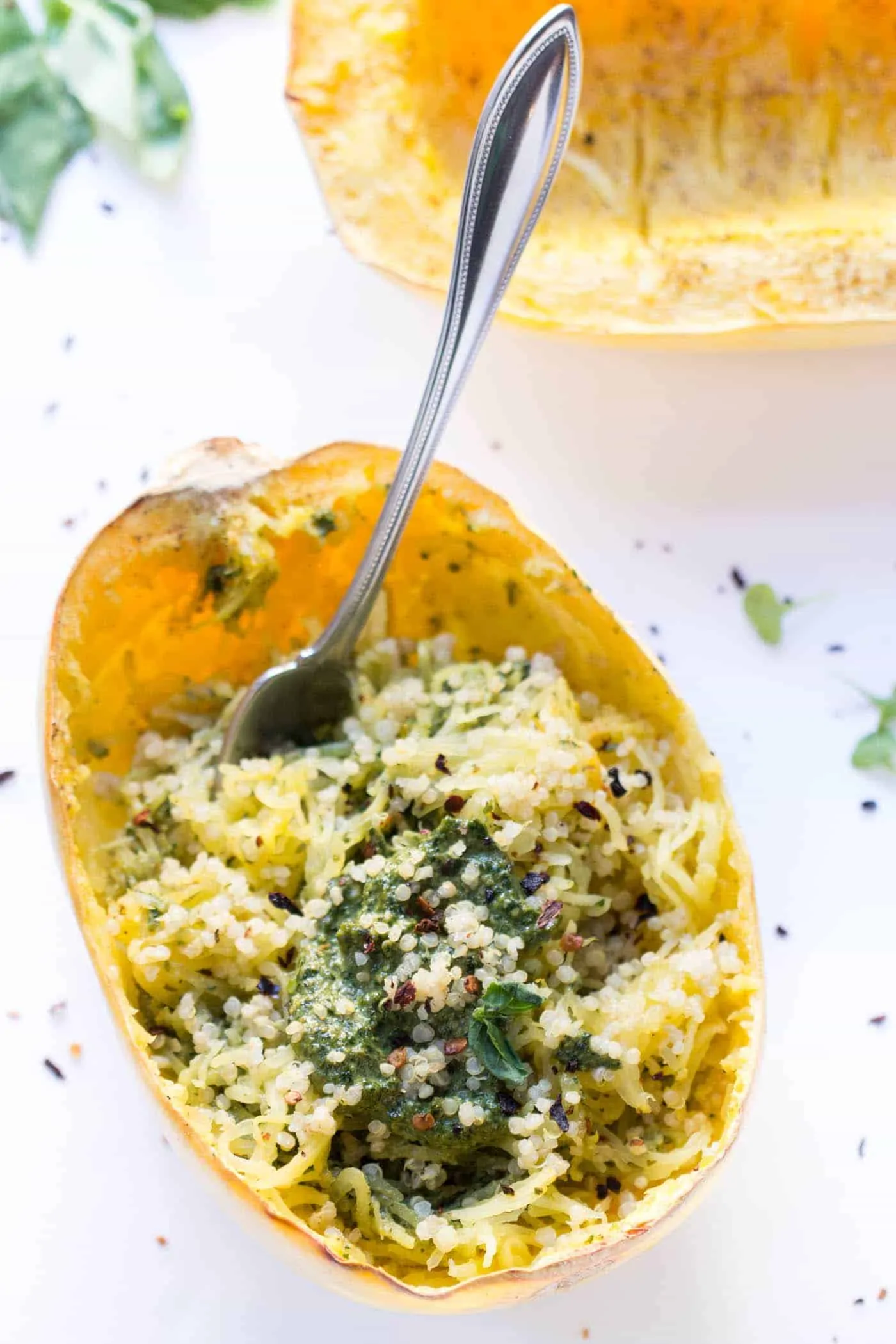This pesto spaghetti squash is an easy meatless meal filled with quinoa and the bright, citrusy flavors of basil pesto. Only 5 ingredients! A fork stuck into spaghetti squash filled with quinoa and pesto.