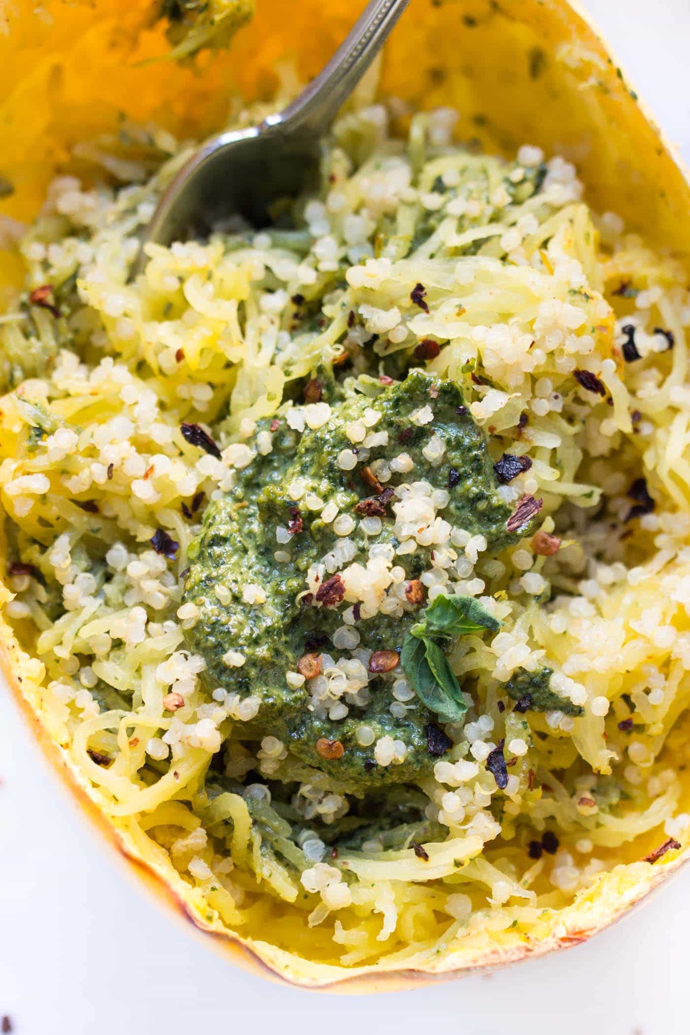 Close up of a fork stuck into pesto spaghetti squash.