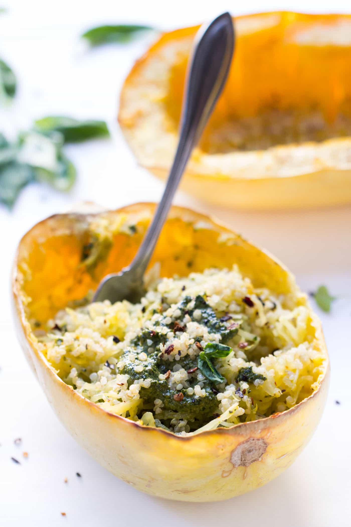 A fork stuck into spaghetti squash filled with quinoa and pesto.