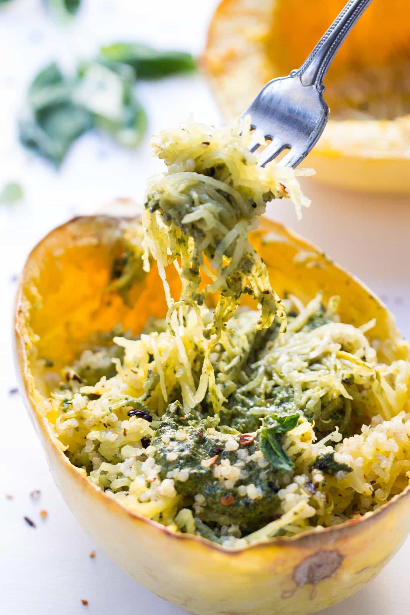 A forkful held over spaghetti squash filled with quinoa and pesto.