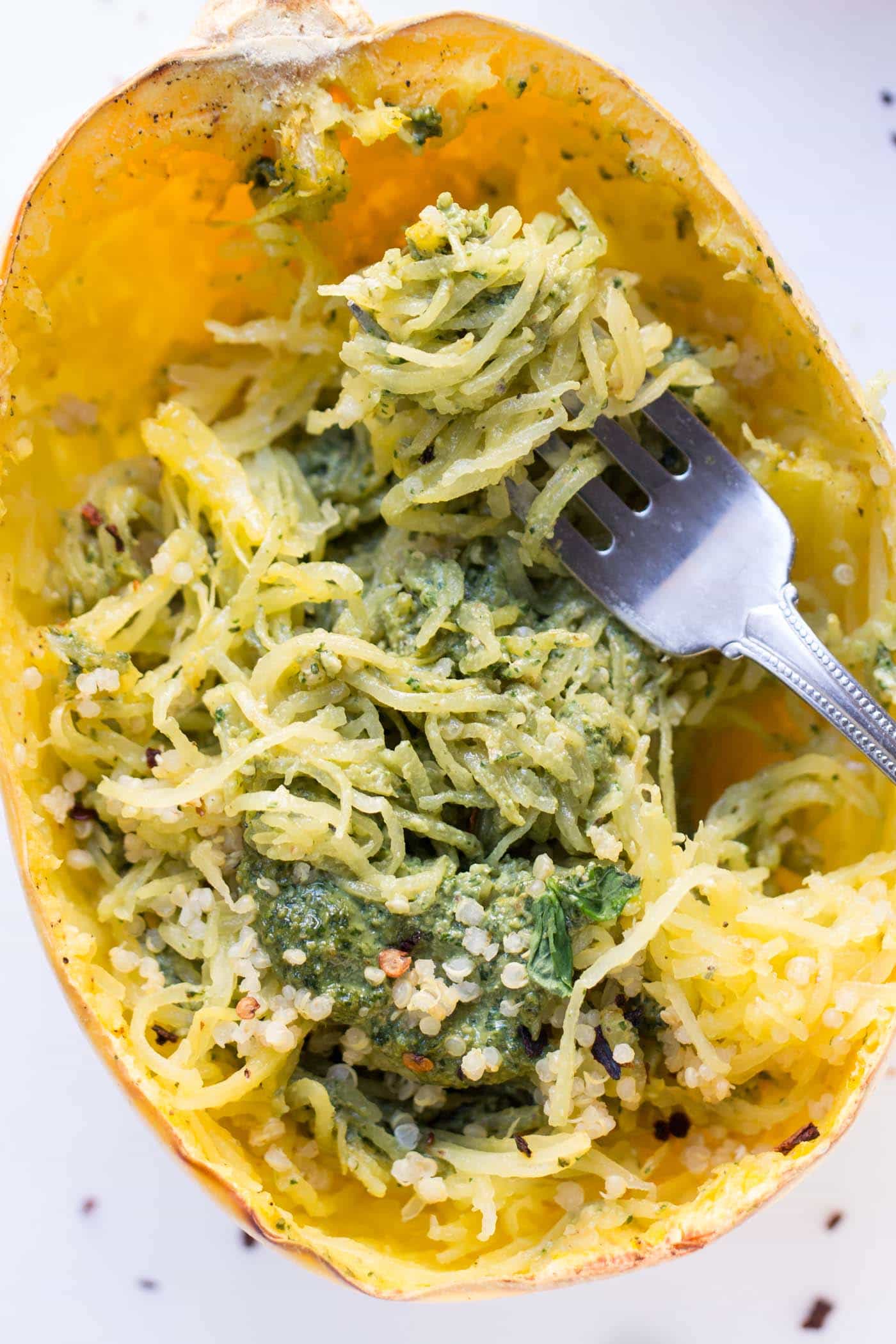 Close up of pesto spaghetti squash swirled around a fork inside a squash boat.