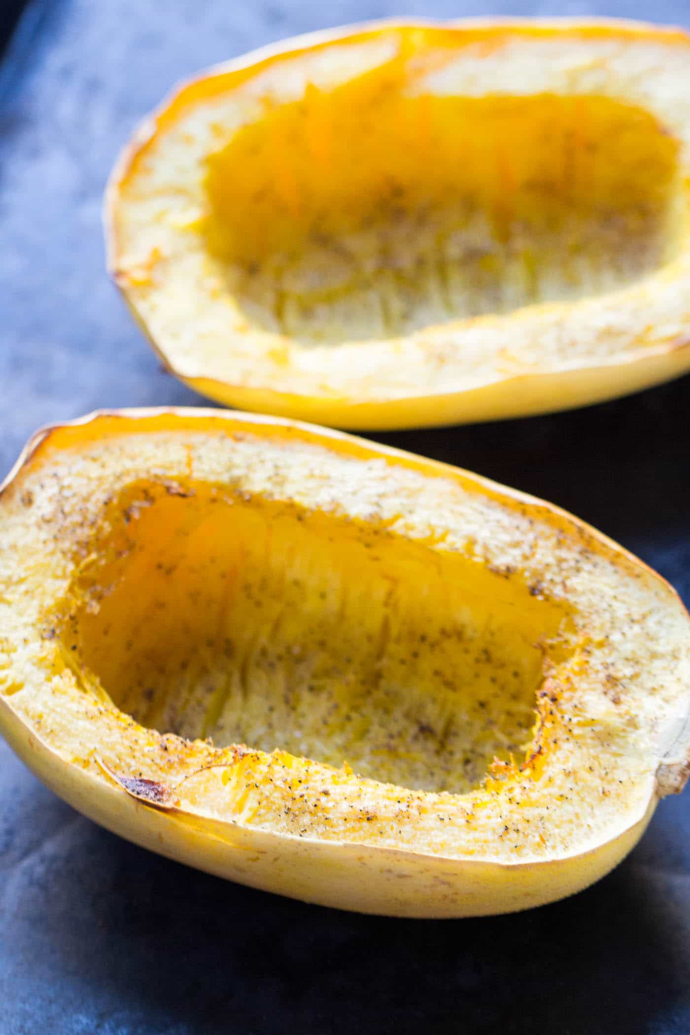 Two hollowed out baked spaghetti squash halves on a countertop.