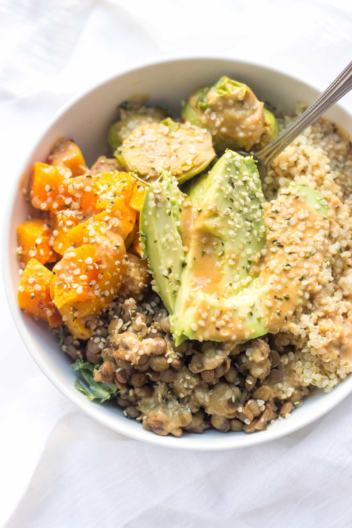 AMAZING and easy quinoa buddha bowls will make you feel all cozy with roasted veggies and creamy avocado -- topped with tahini and hemp seeds!