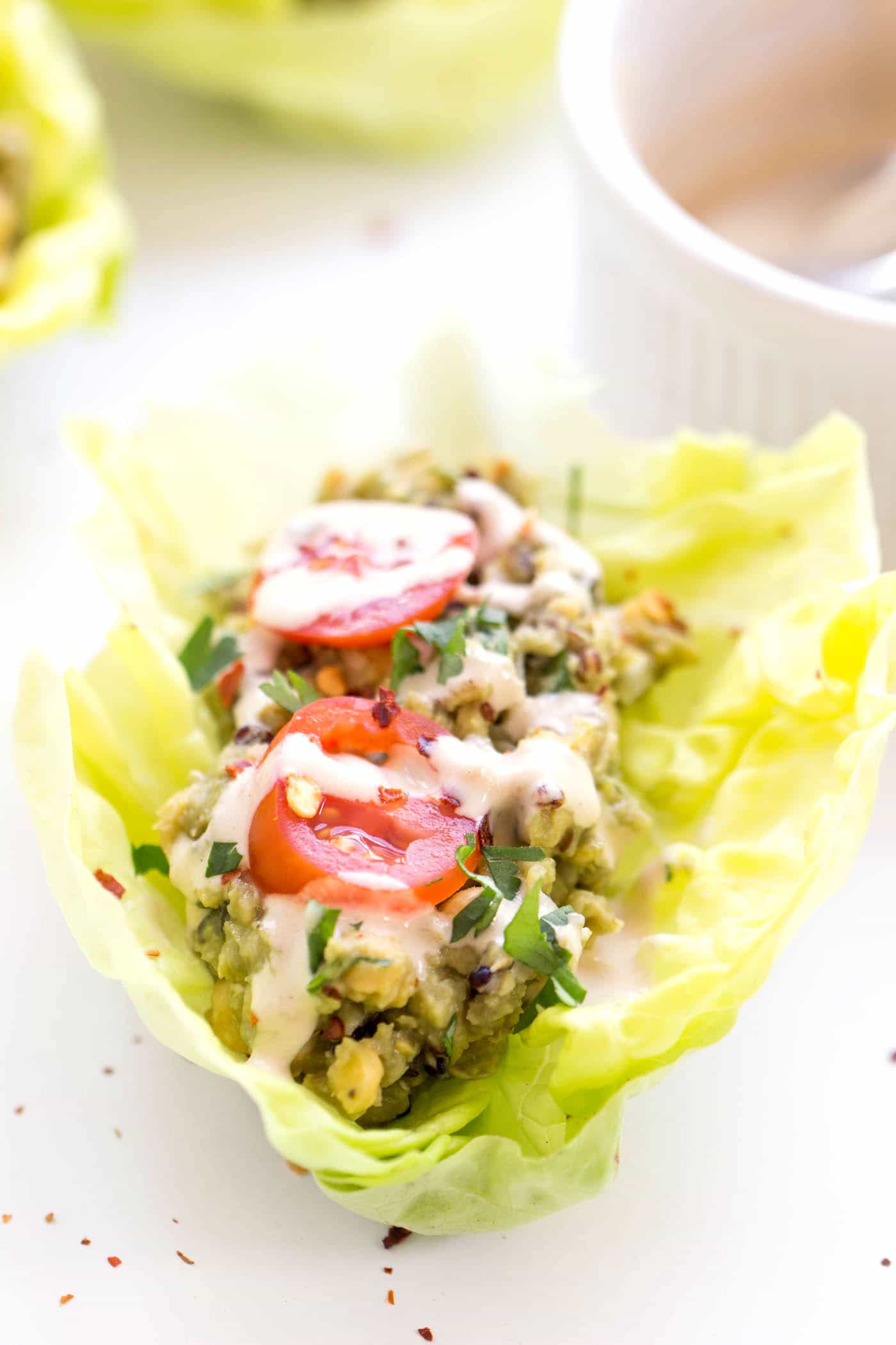 QUINOA LETTUCE WRAPS with a smashed chickpea + avocado salad, topped with sliced cherry tomatoes and drizzled with tahini. Plant-based, high-protein and surprisingly filling! [gluten-free + vegan]
