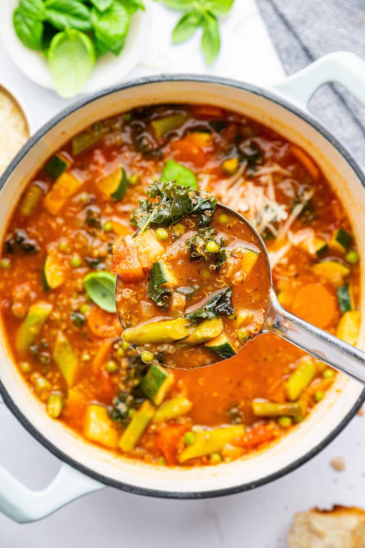 Ladleful of vegetarian minestrone soup held over pot