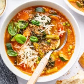Overhead view of vegetarian minestrone soup in bowl with spoon
