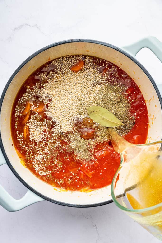 Pouring broth into pot of soup