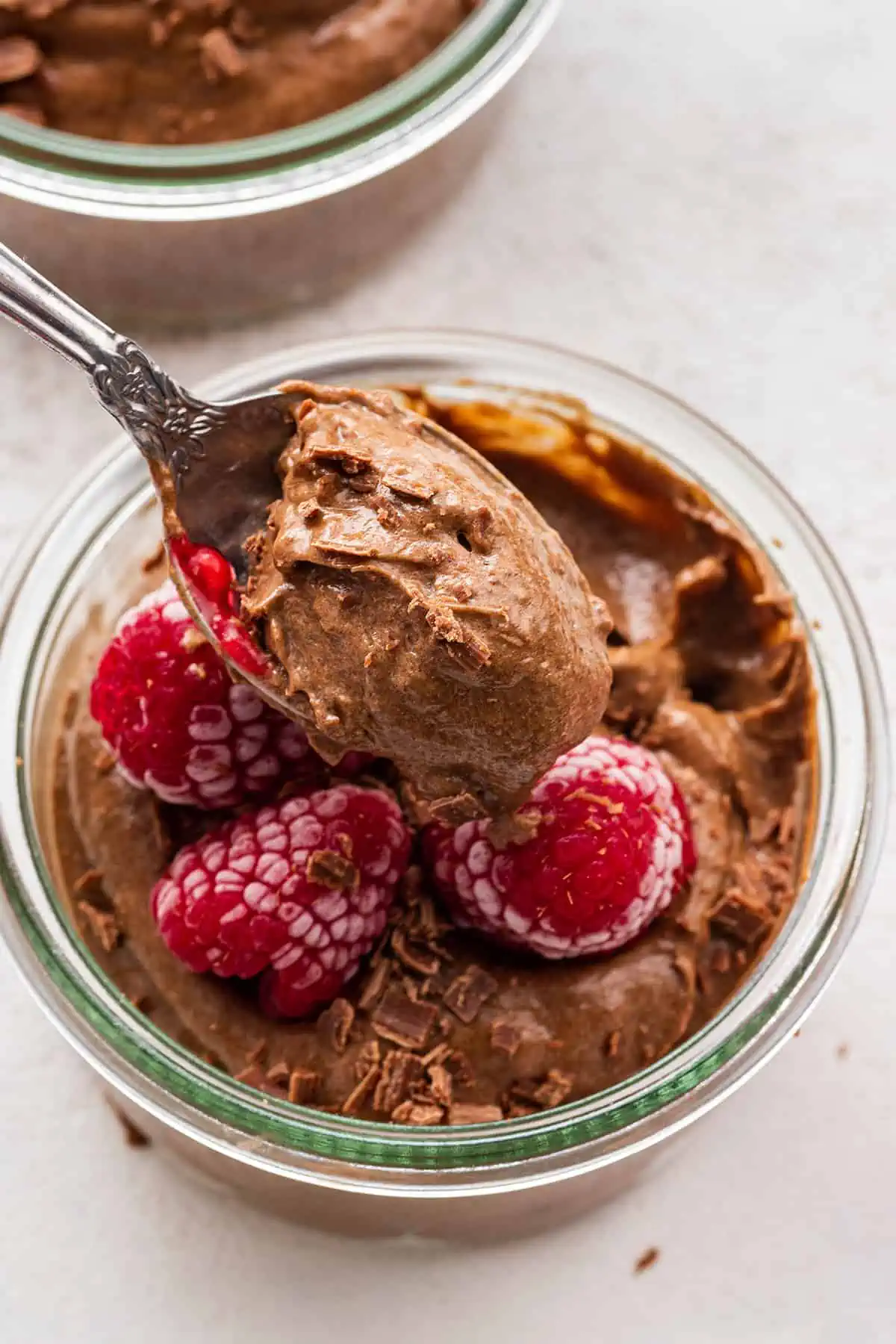 A spoon with a biteful of creamy chocolate avocado mousse