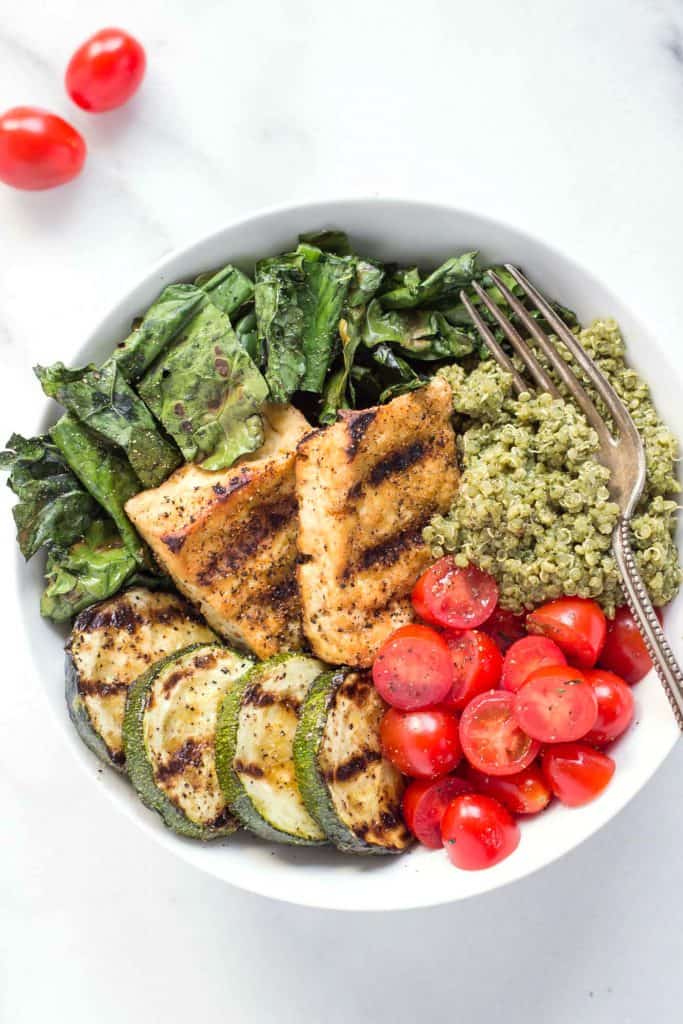 bowl of pesto quinoa with grilled tofu, tomatoes, grilled zucchini and kale