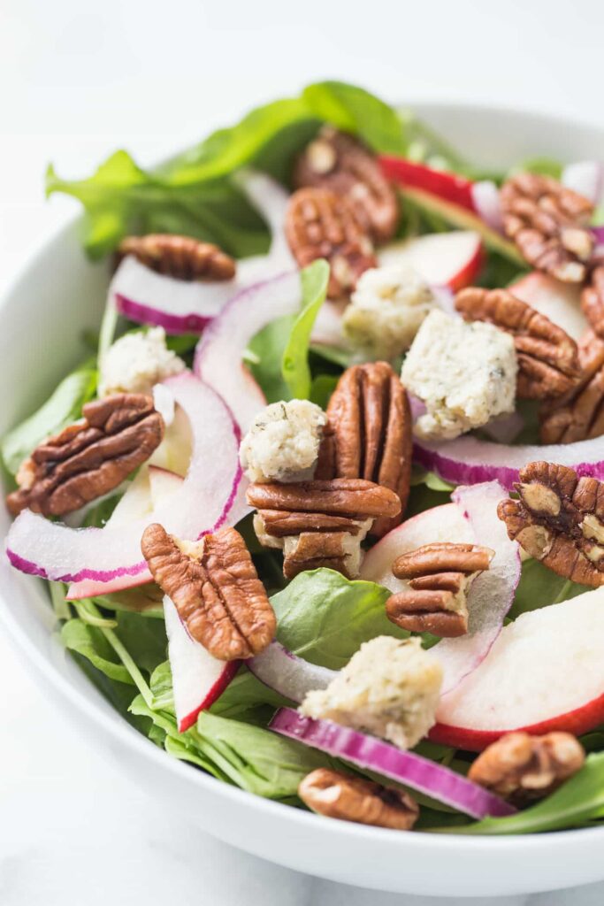 A super simple APPLE + PECAN ARUGULA SALAD topped with herbed cashew cheese and a maple-tahini dressing!