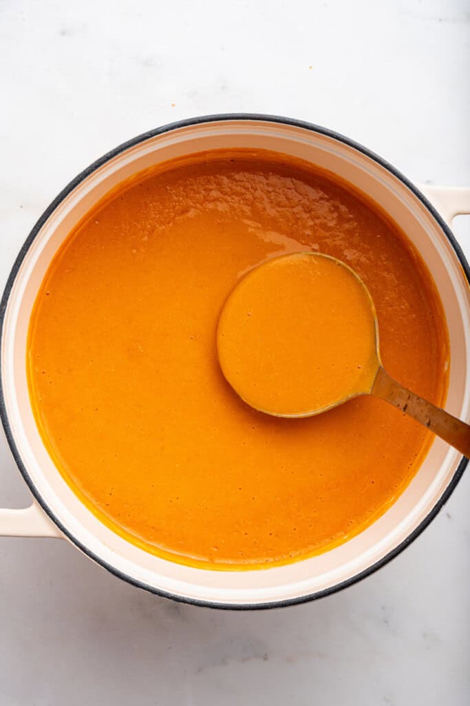Finished tomato bisque in a dutch oven with a ladle.